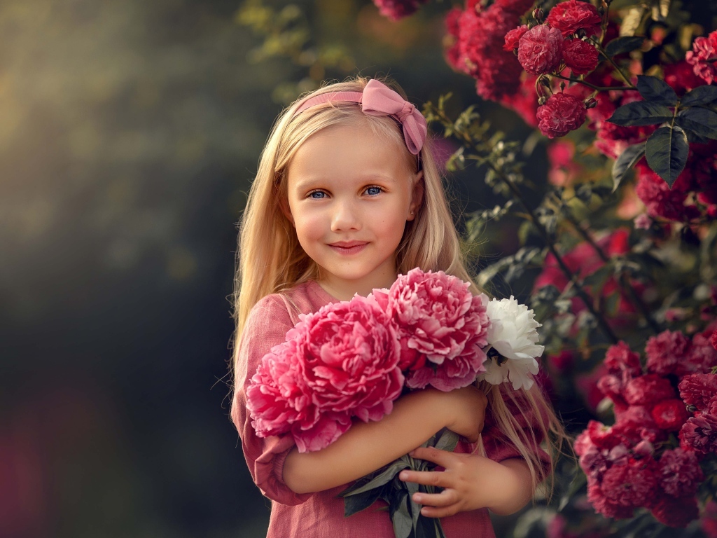 Милая маленькая девочка с букетом пионов