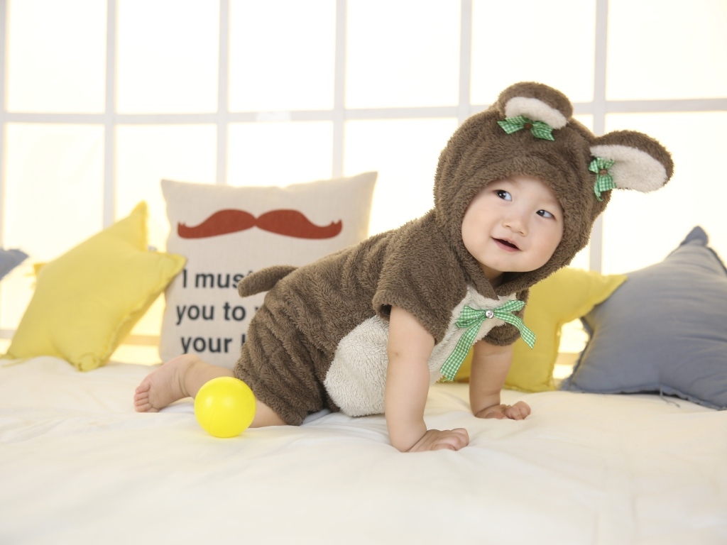 Смешной ребенок азиат в костюме на кровати