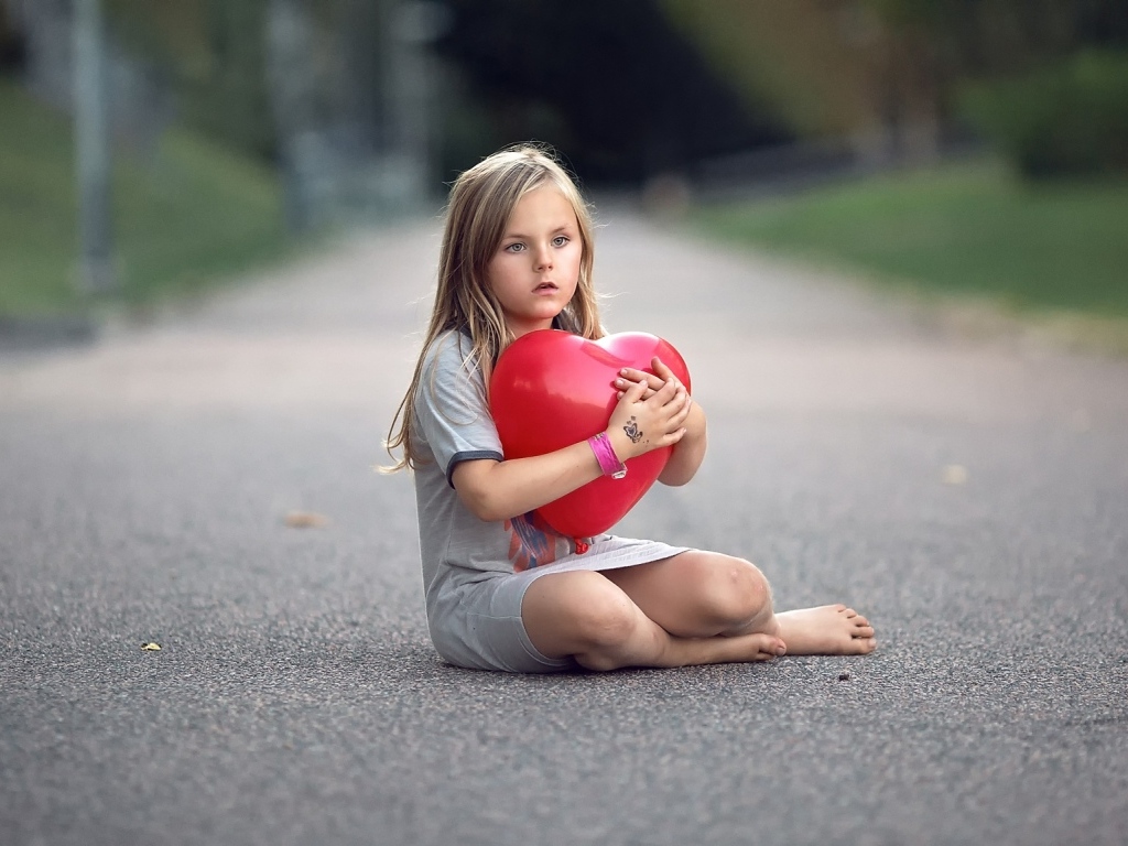 Девочка сидит на дороге с шариком в форме сердца