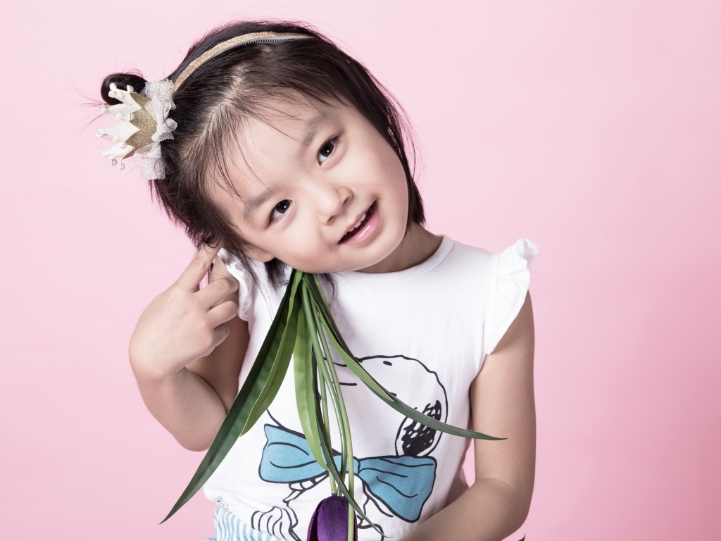 Маленькая девочка азиатка на розовом фоне