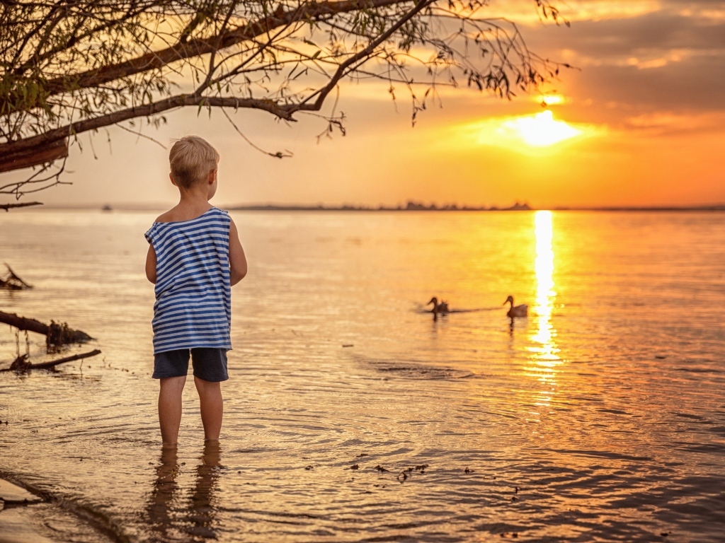 Маленький мальчик в тельняшке у озера на закате