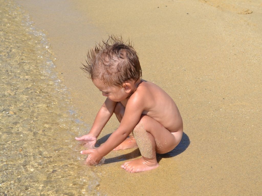 Маленький мальчик на пляже у моря на песке