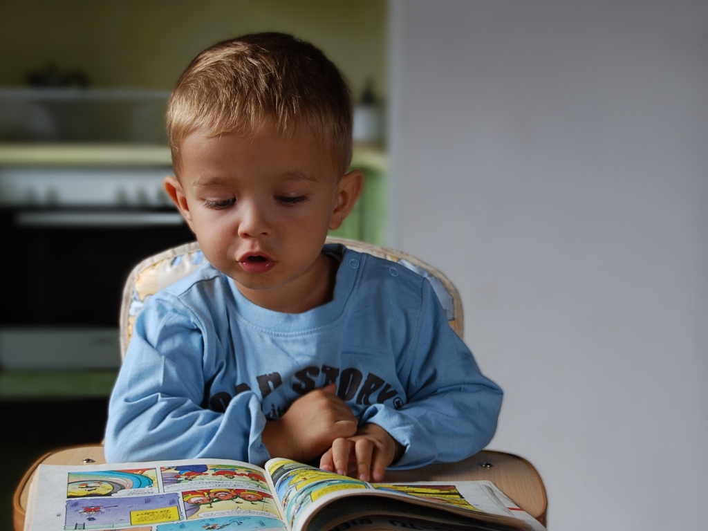 Маленький мальчик читает интересную книгу