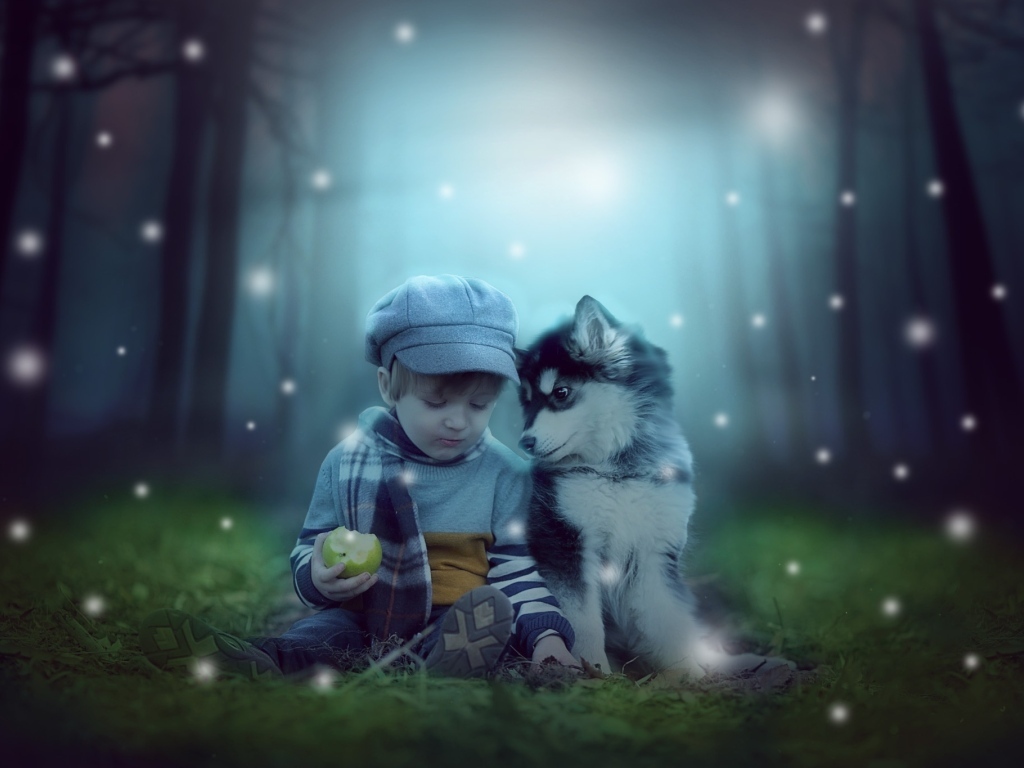 Маленький мальчик с щенком сидят на траве в лесу