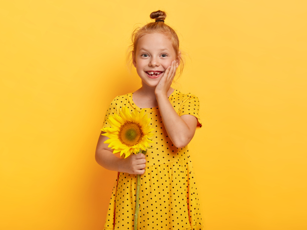 Маленькая рыжеволосая девочка с подсолнухом в руках