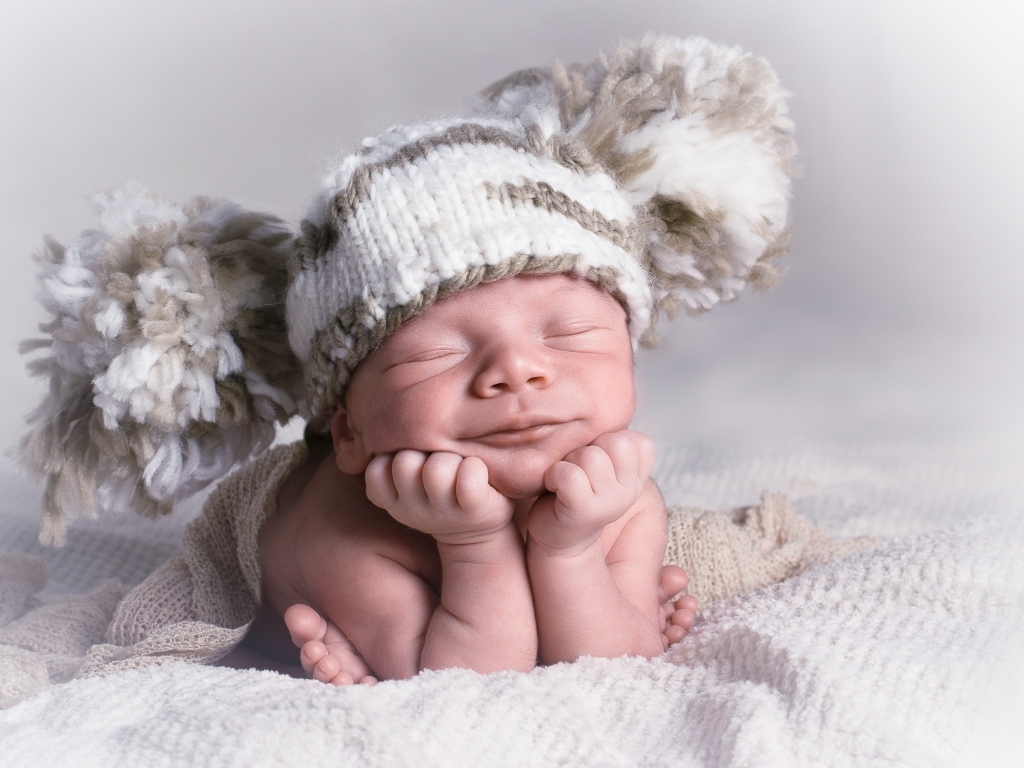 Новорожденный младенец в большой вязаной шапке