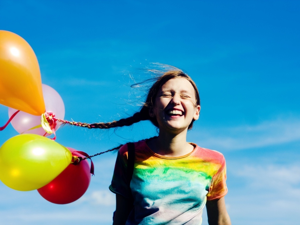 У веселой девочки шарики привязаны к косам