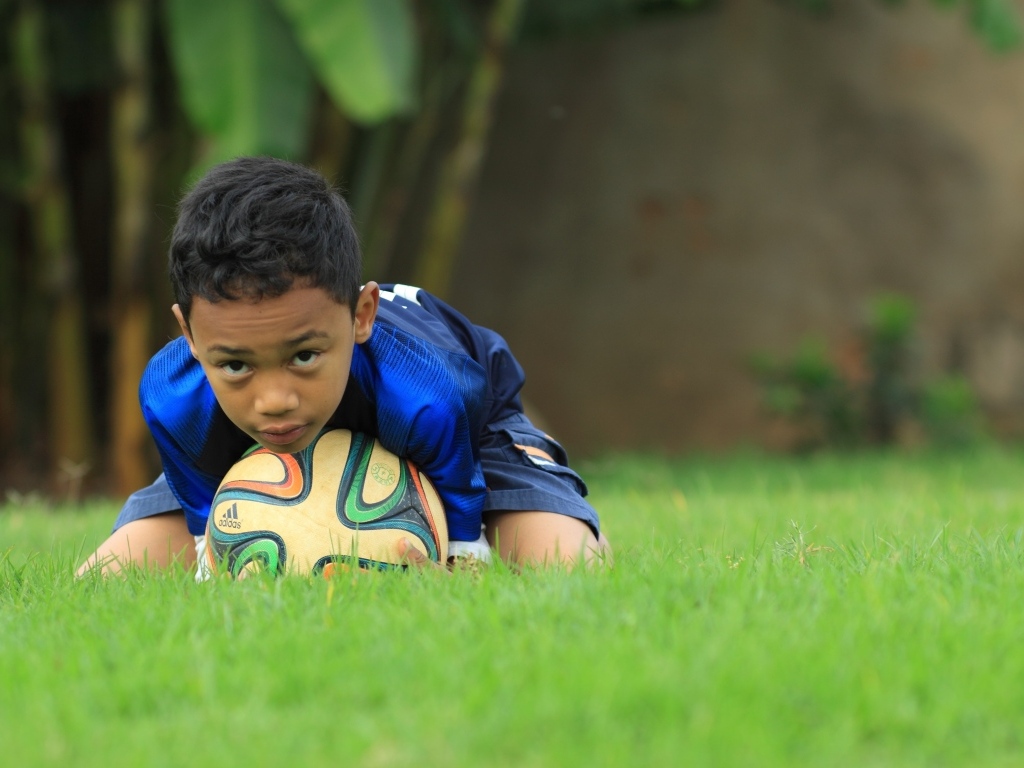 Мальчик юный футболист с мячом на поле