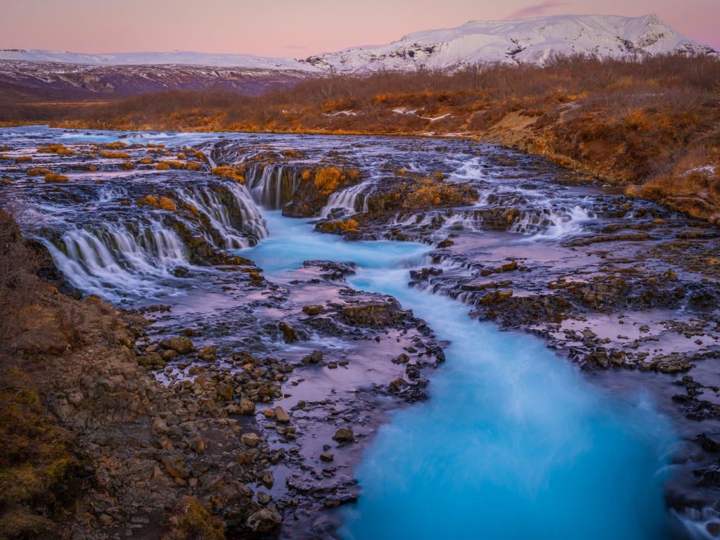 Быстрая река стекает по камням в горах Исландии