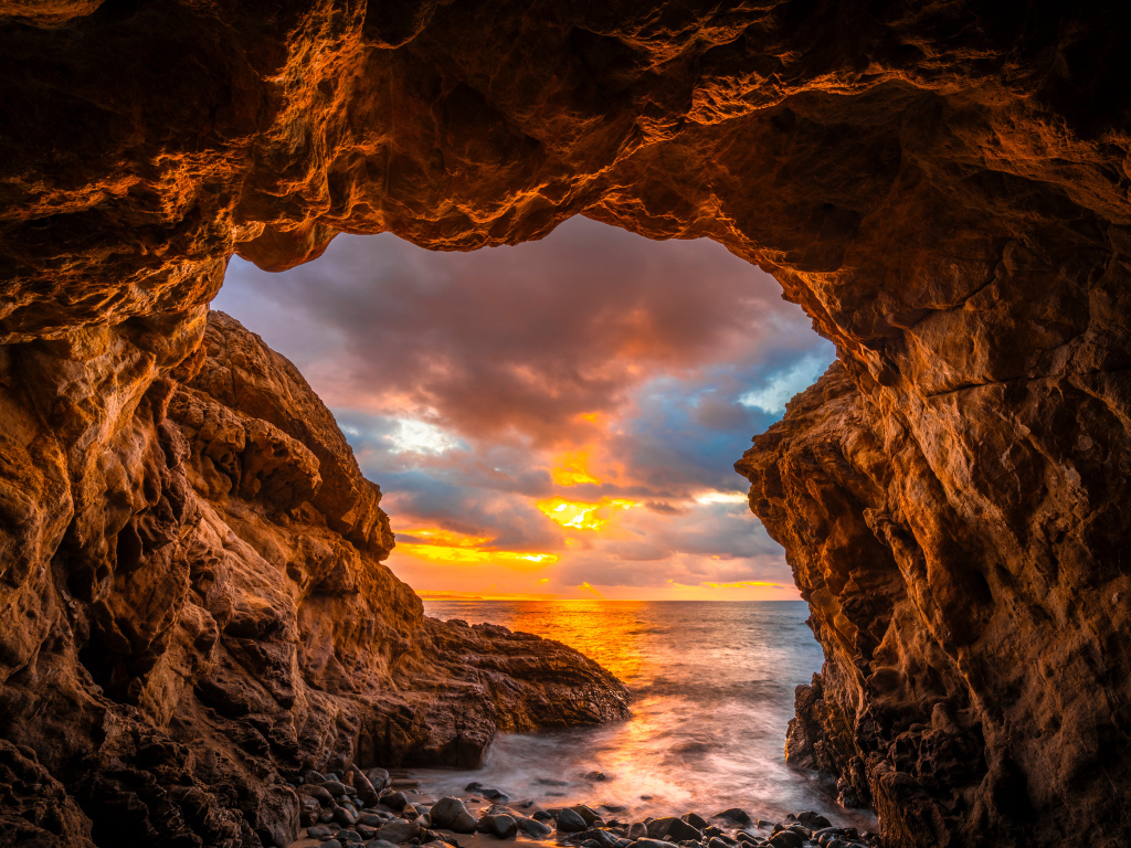 Арка в горе на закате солнца на пляже Малибу, США