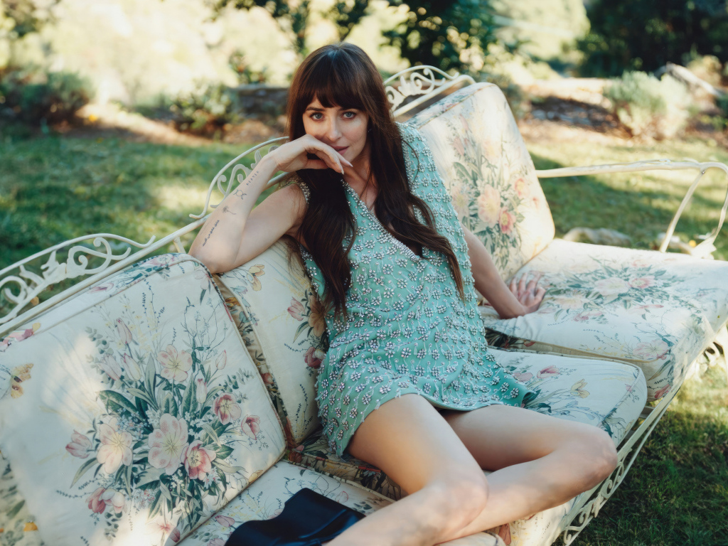 Актриса Дакота Джонсон в платье сидит на диване