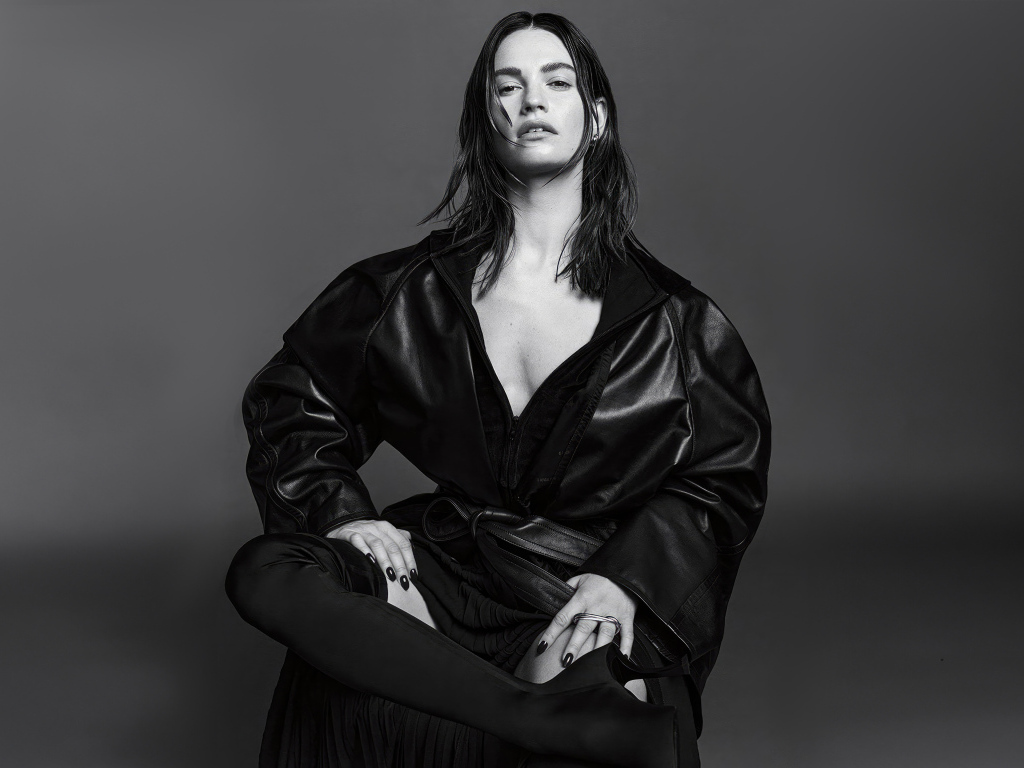 Актриса Лили Джеймс в черном наряде на сером фоне