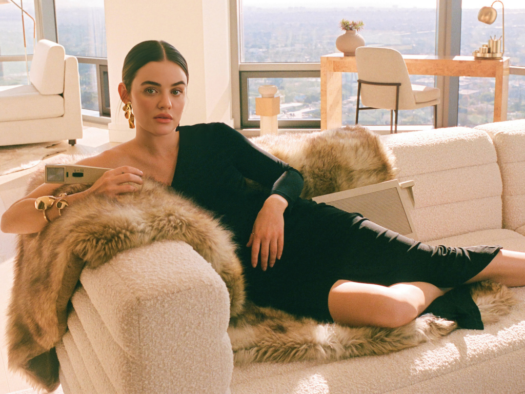 Актриса Люси Хейл в черном платье лежит на диване