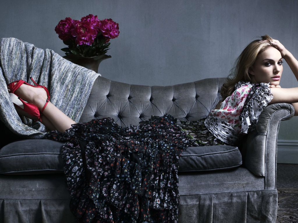 Актриса Натали Портман в платье лежит на сером диване