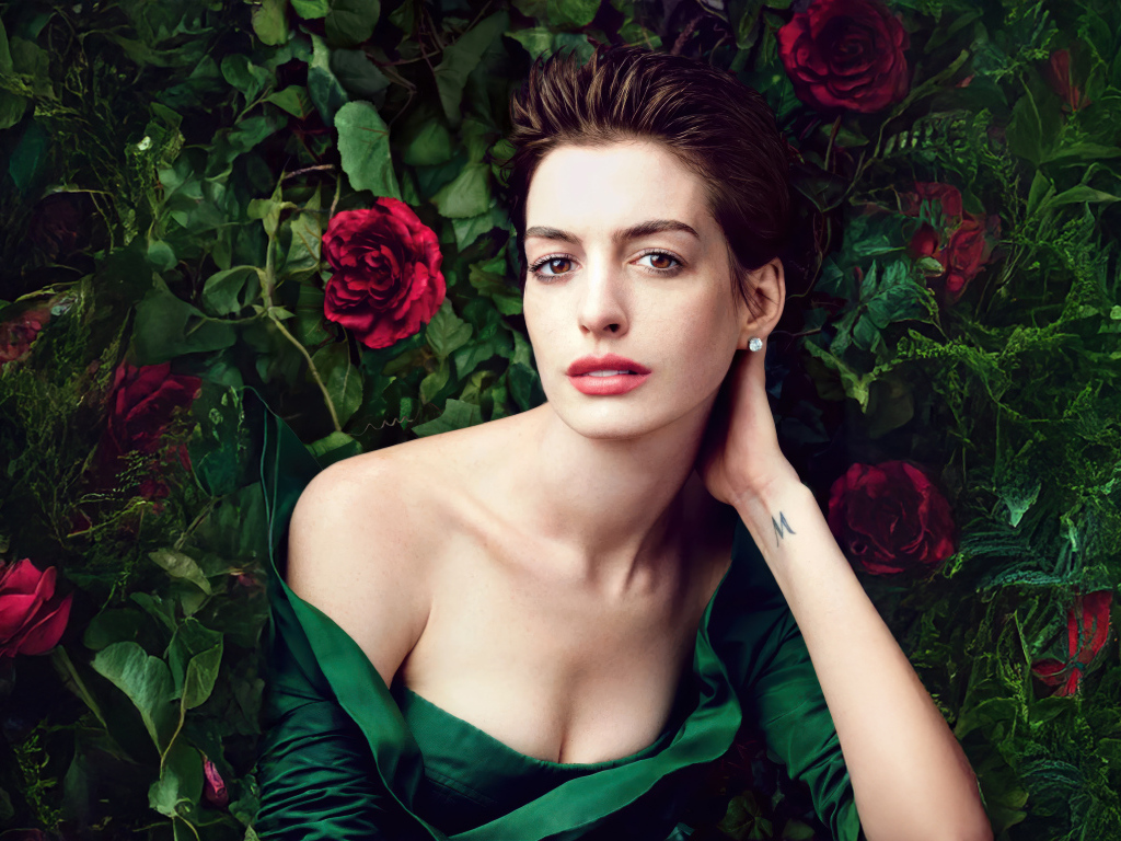 Красивая актриса Энн Хэтэуэй в зеленом платье на фоне роз