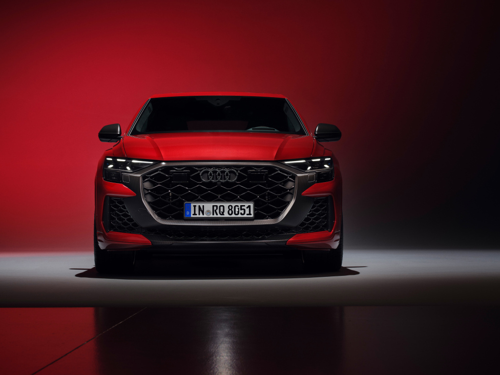 Вид спереди на автомобиль Audi RS Q8 performance 2024 года на красном фоне