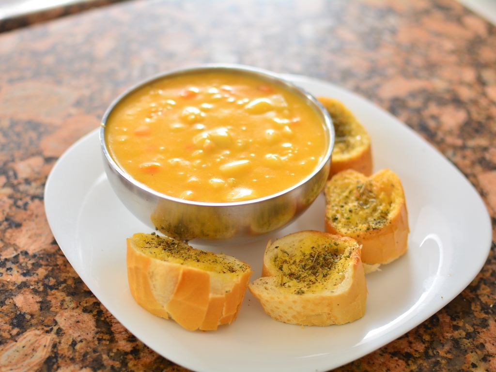 Суп с фасолью на тарелке с гренками