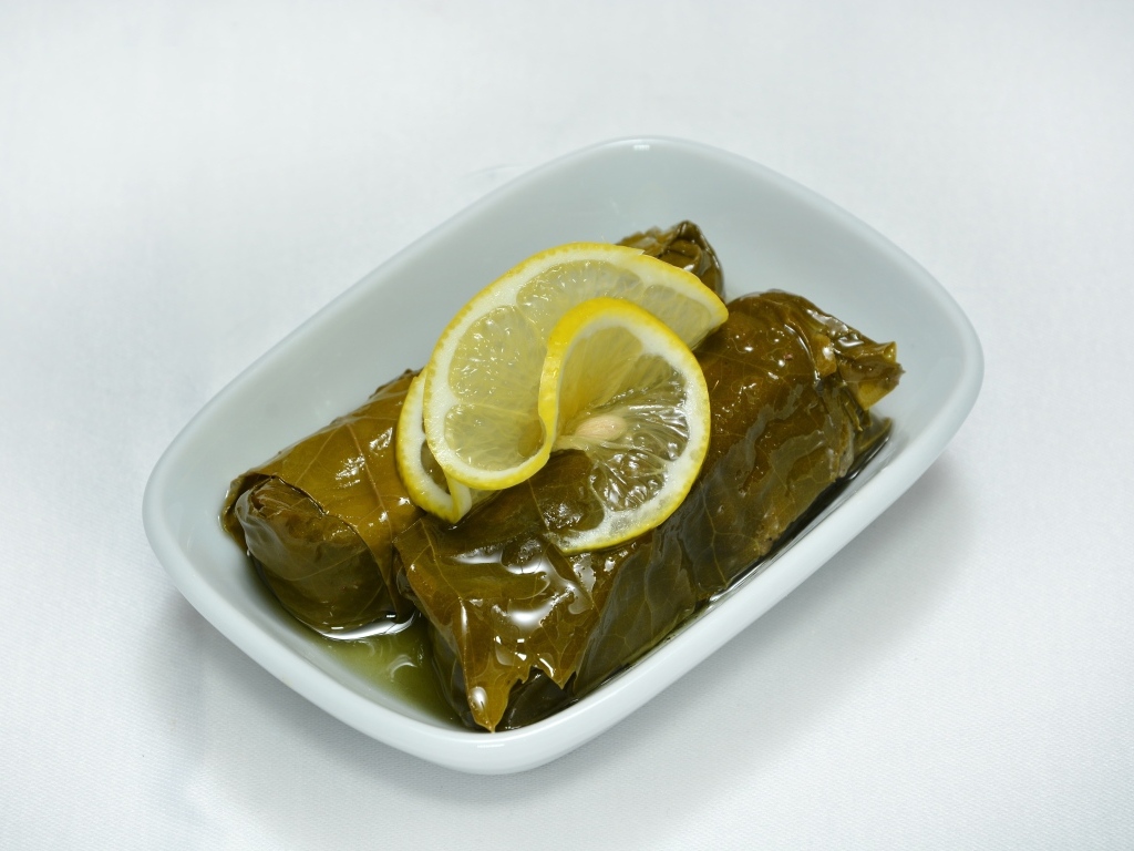 Долма с лимоном с тарелке на сером фоне