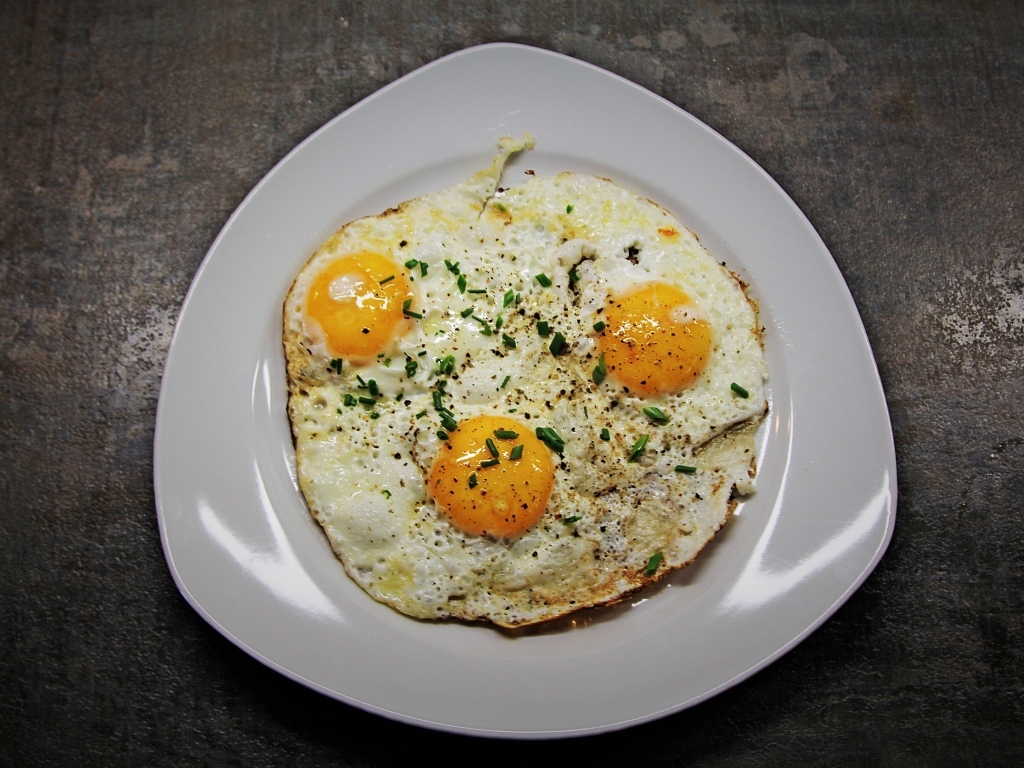 Яичница глазунья в тарелке на сером столе