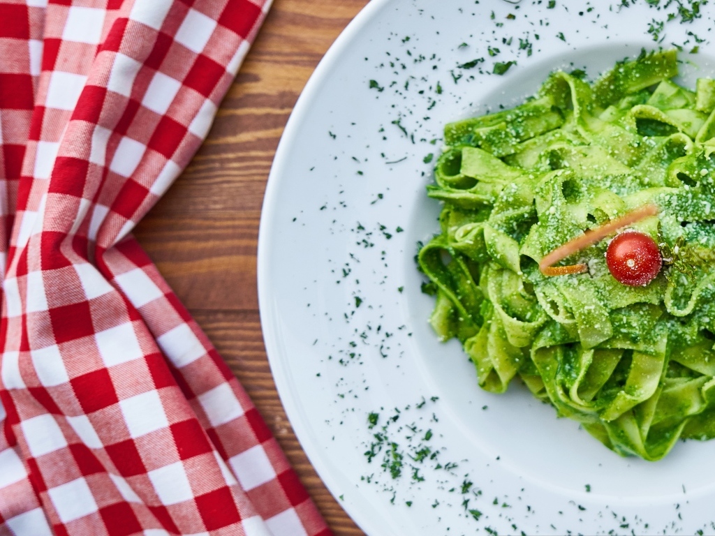 Зеленая паста на белой тарелке 