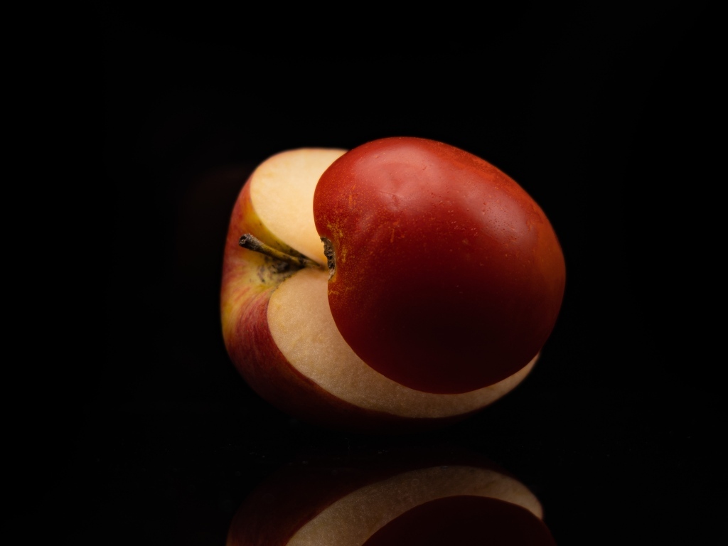 Разрезанное на половинки красное яблоко на черном фоне