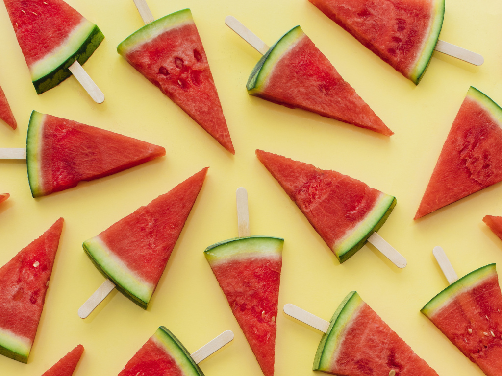 Куски арбуза на палочке на желтом фоне