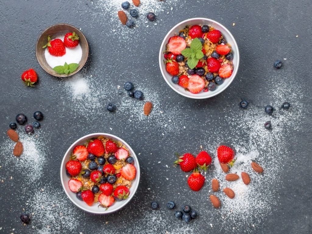 Тарелки с мюсли и ягодами на сером столе с пудрой