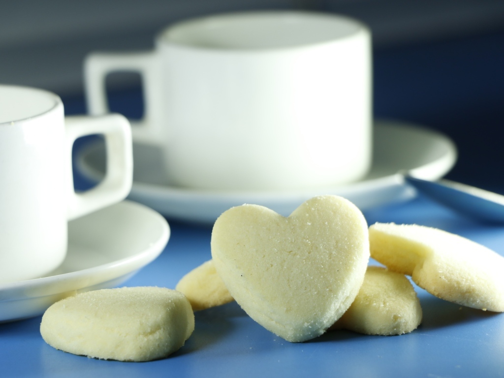 Сладкое печенье в форме сердца с кружками на столе