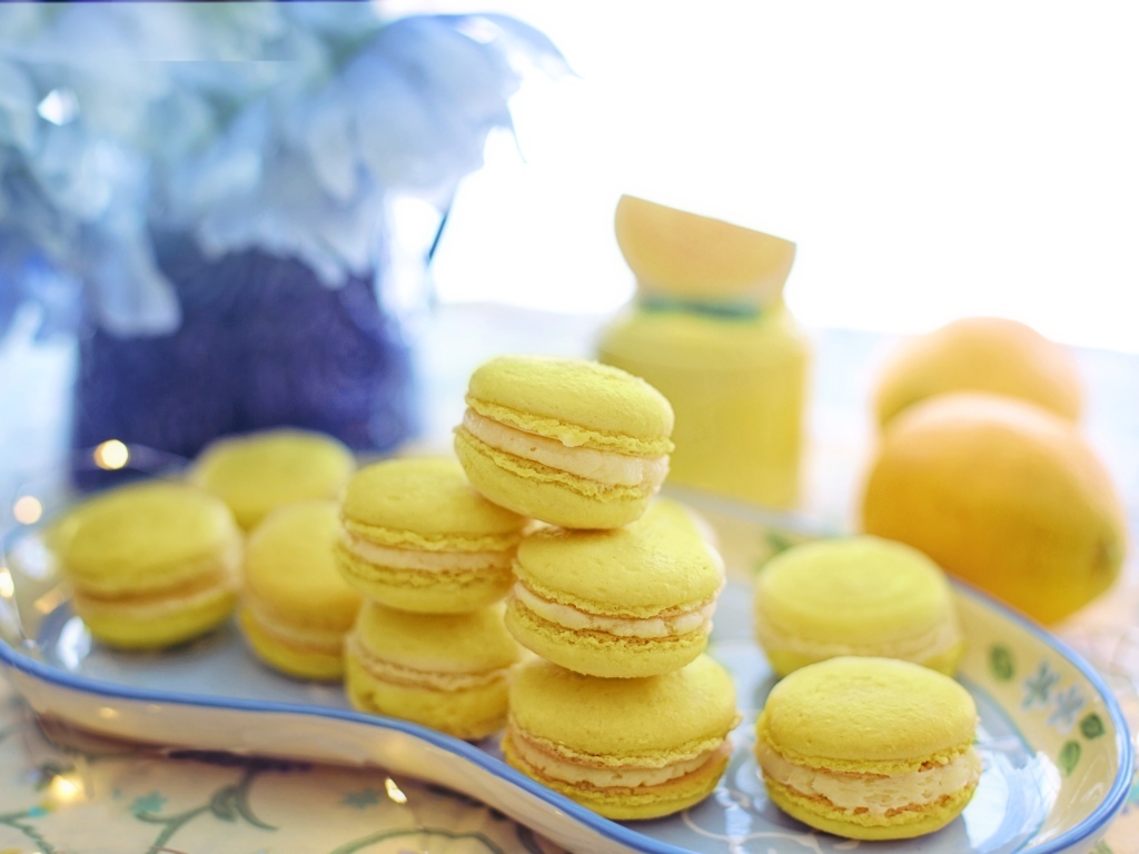 Десерт макарунс желтого цвета на тарелке на столе