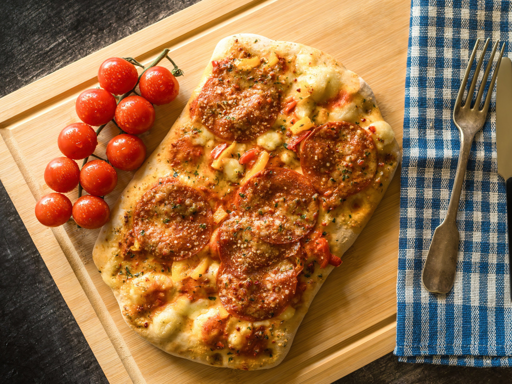 Пицца с колбасой и помидорами на доске