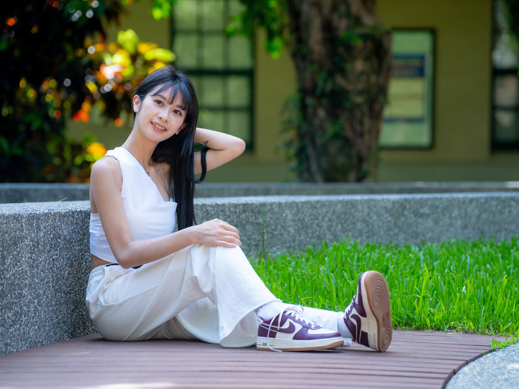 Девушка азиатка в белой костюме сидит на земле