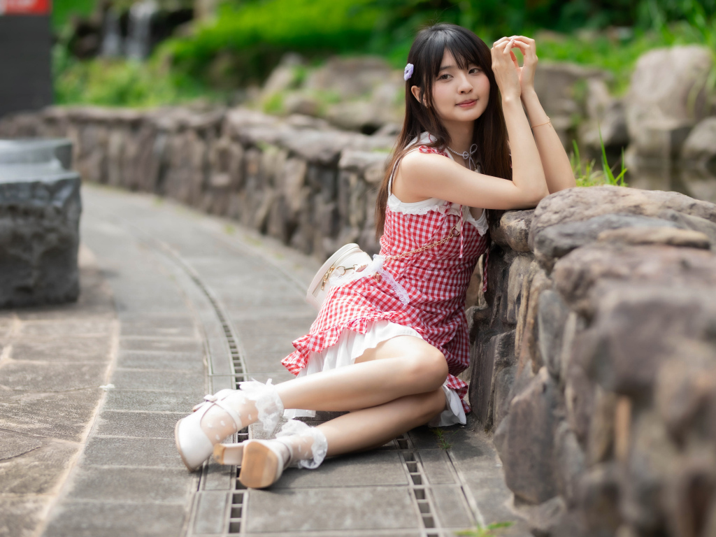 Азиатка сидит на земле в красном платье