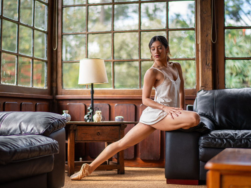 Девушка балерина делает шпагат в комнате