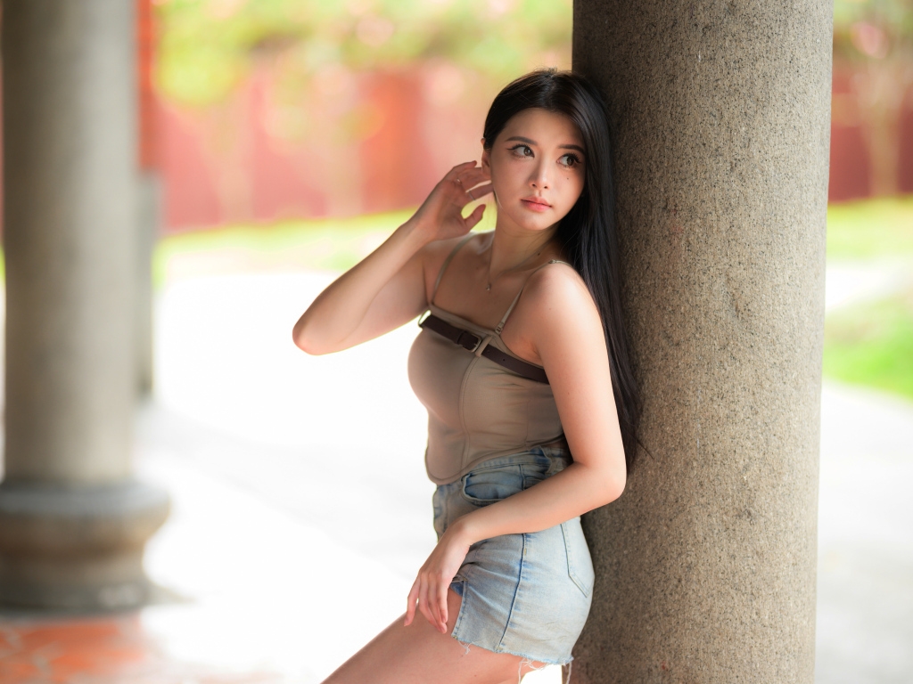 Милая длинноволосая азиатка стоит у колонны
