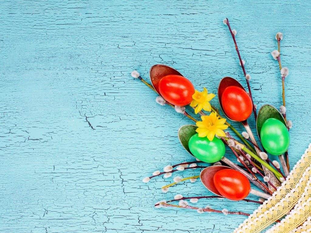 Ложки с разноцветными яйцами и ветками вербы на голубом фоне на Пасху