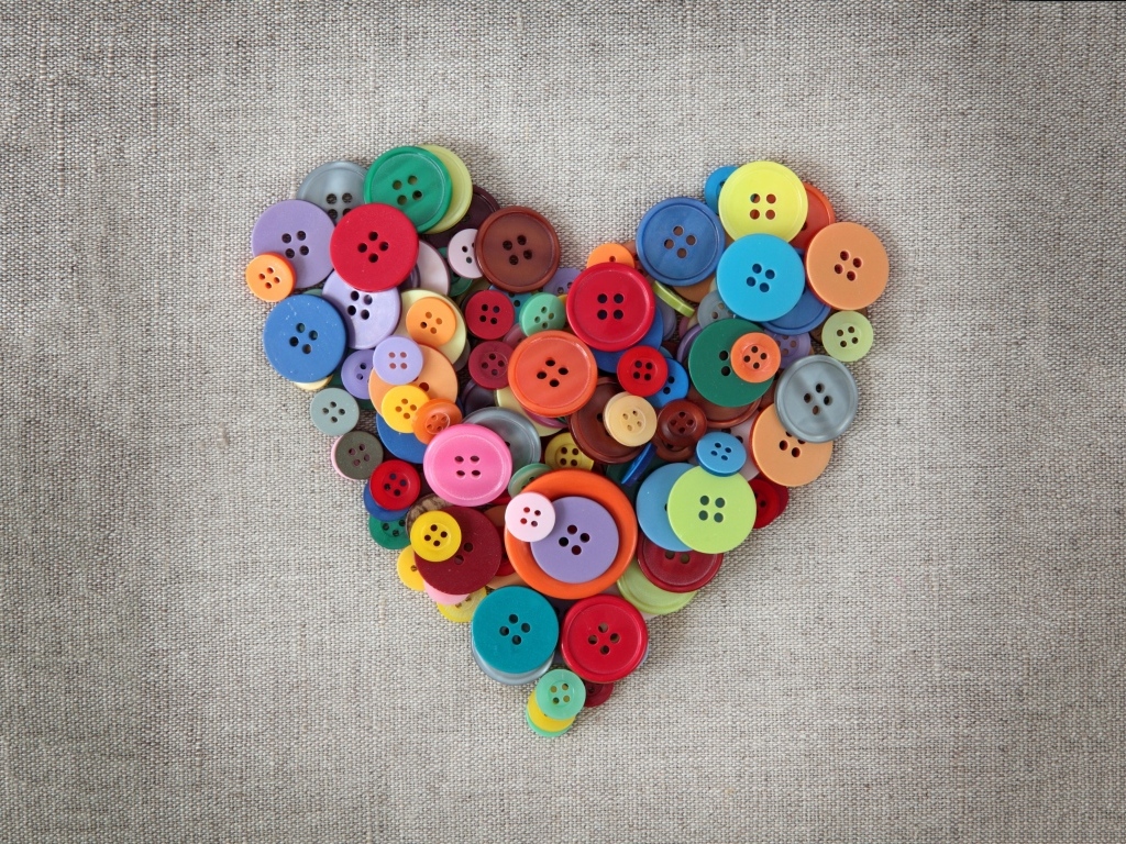 Сердце из разноцветных пуговиц на ткани 