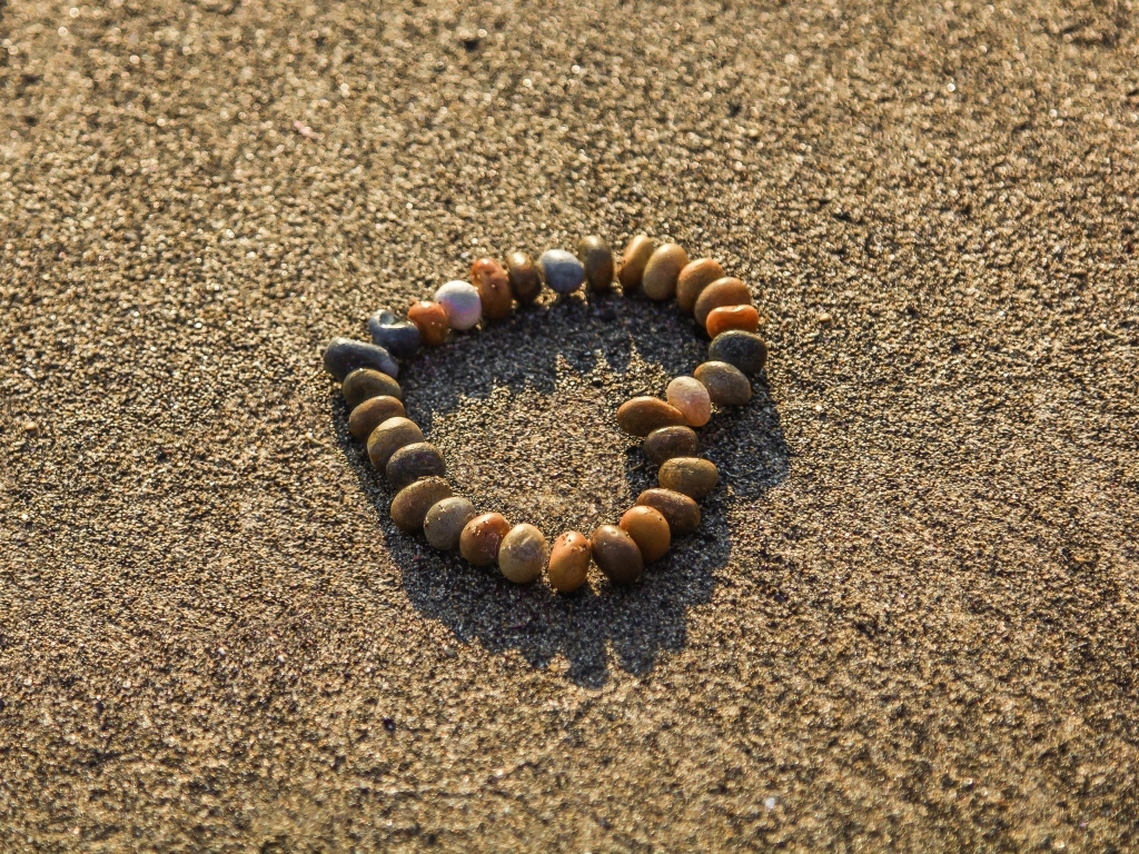 Сердце из камней на морском песке летом