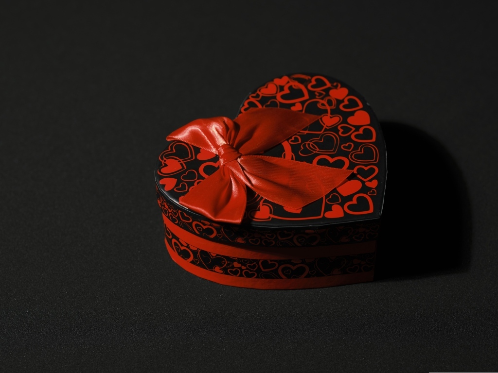 Шкатулка в форме сердца с красным бантом на черном фоне