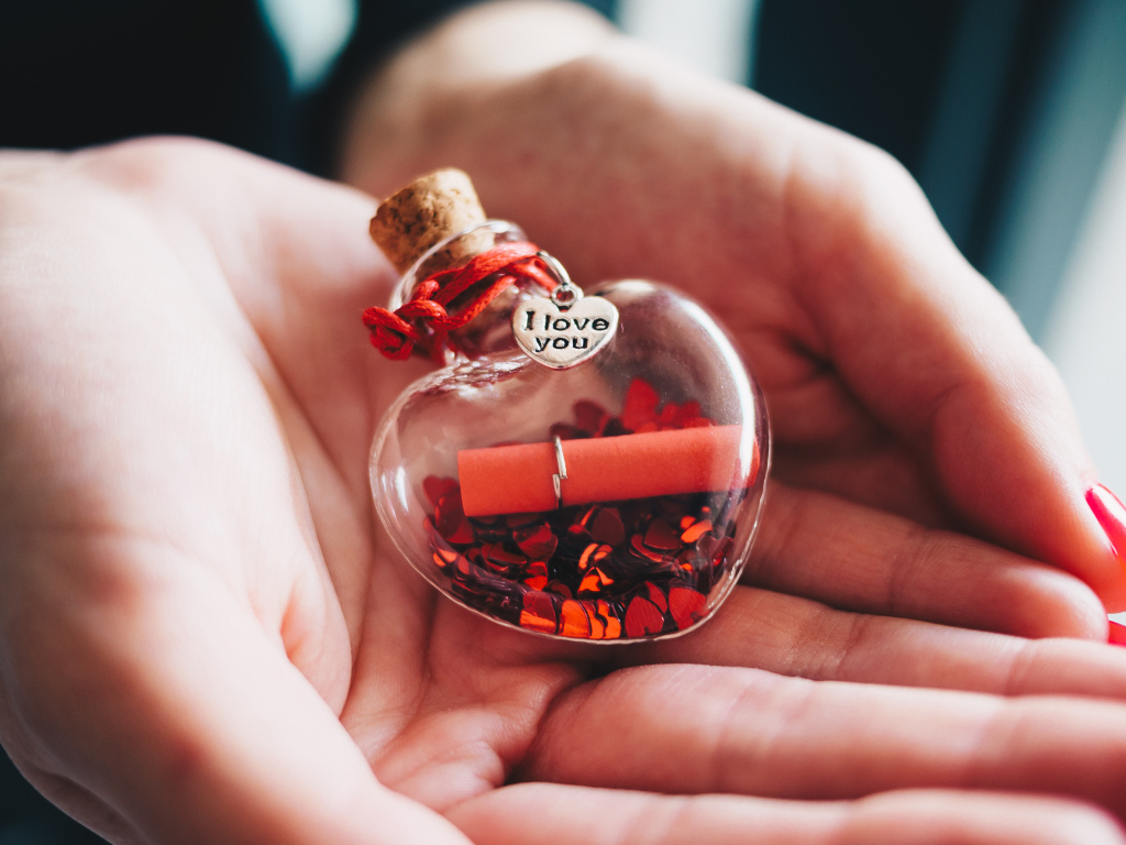 Ладони с маленький стеклянным сердечком