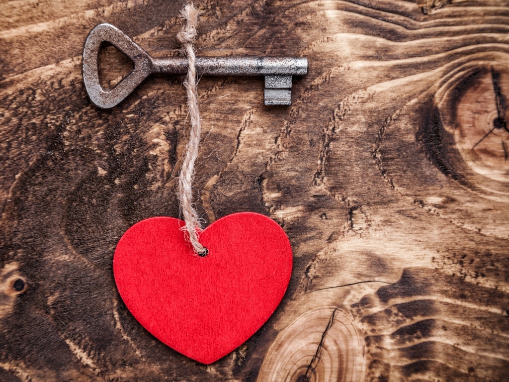 Красное сердце на нитке с ключом на деревянном фоне