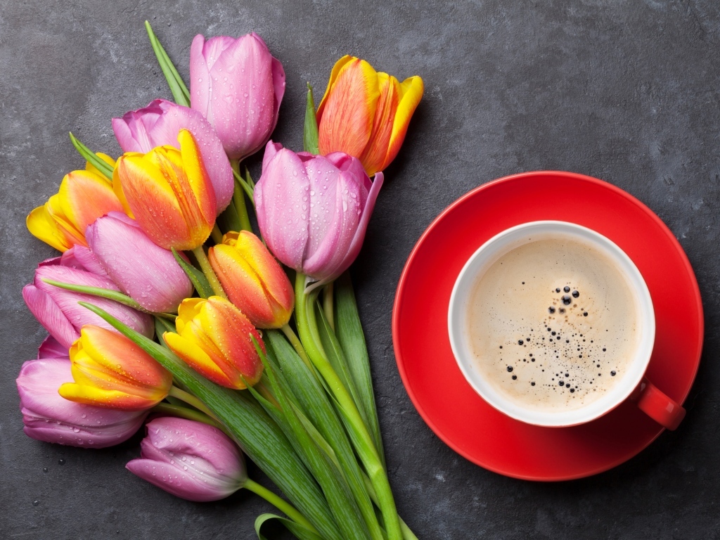 Букет разноцветных весенних тюльпанов на столе с чашкой кофе