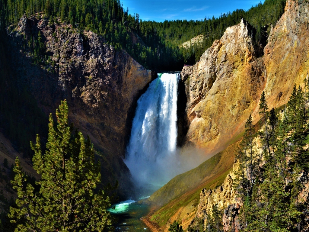 Водопад стекает по крутому склону скалы летом