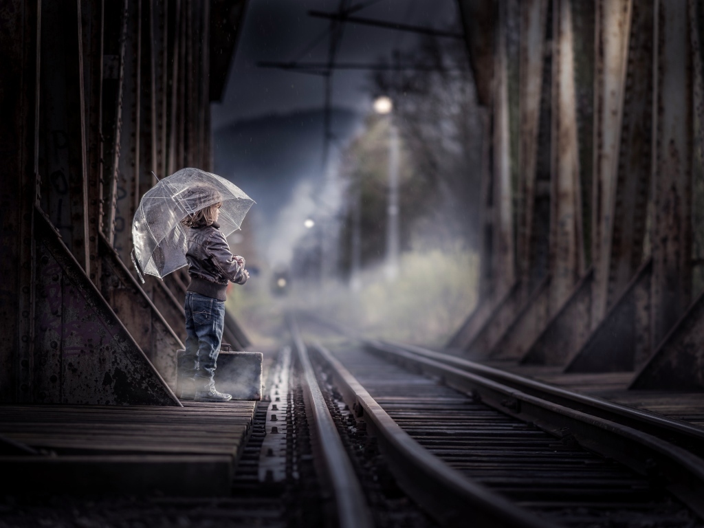 Ребенок под зонтом у железной дороги