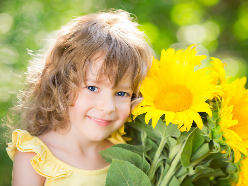 Красивая голубоглазая девочка с букетом подсолнухов