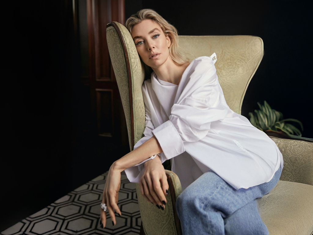 Актриса Ванесса Кирби в белой рубашке сидит на кресле