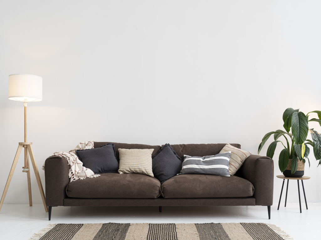 Коричневый диван у серой стены с лампой
