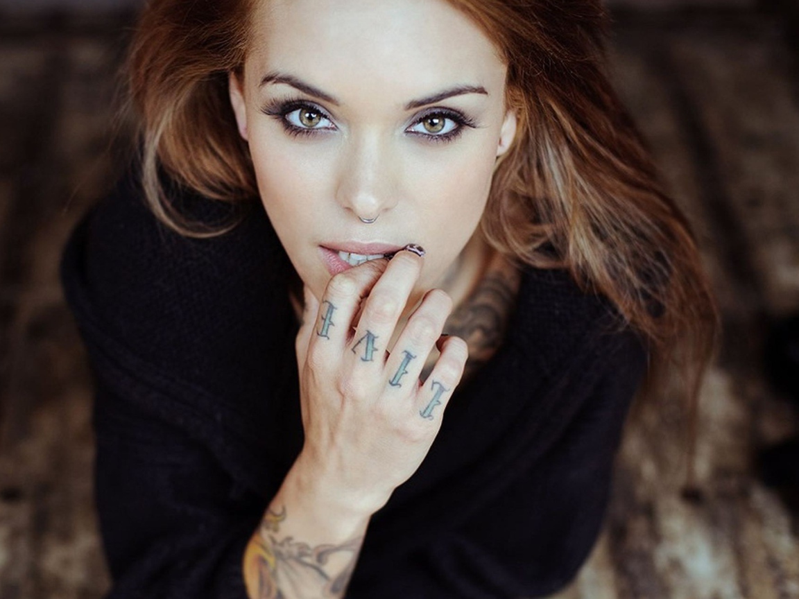 Девушка шатенка с пирсингом в носу и татуировкой на руке