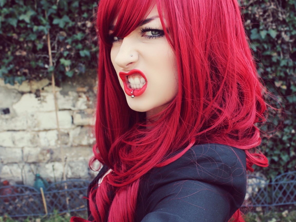 Девушка с красными волосам и пирсингом в носу и губе