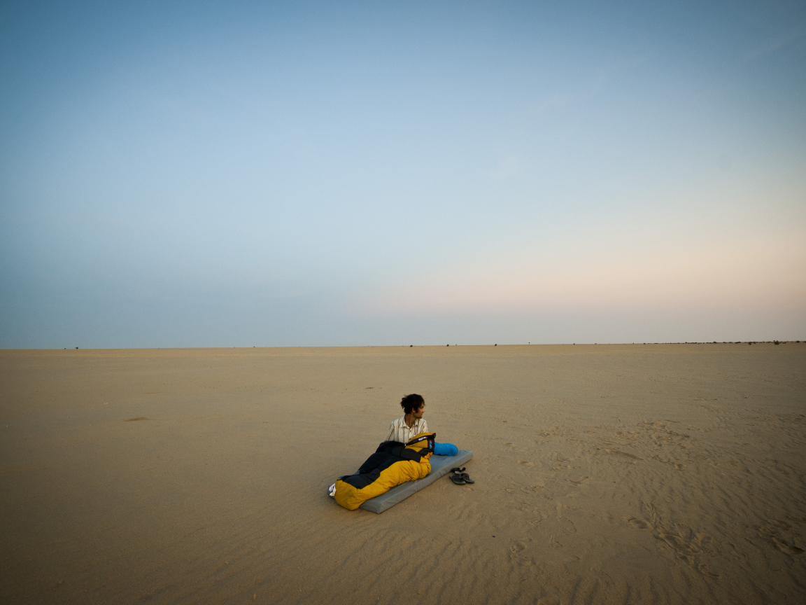 Мужчина на матрасе на пляже