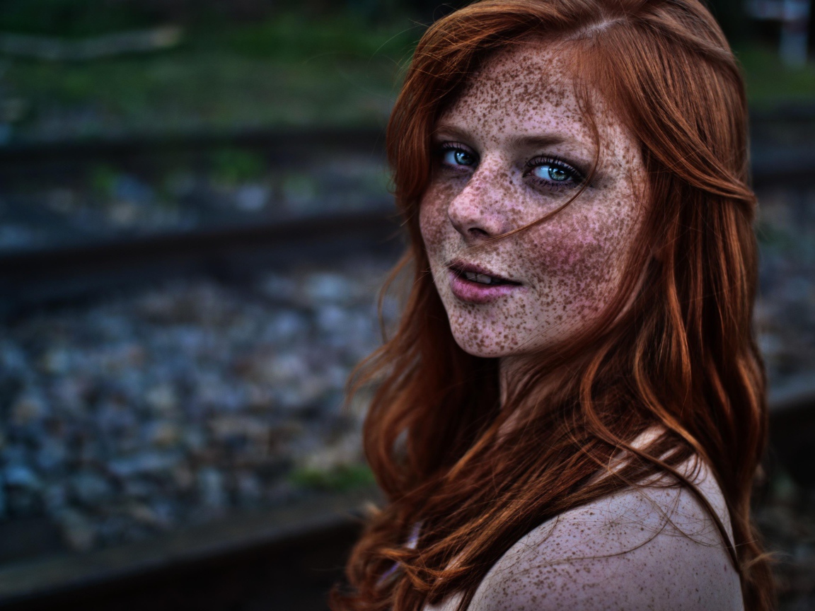 Девушка с веснушками на фоне рельс